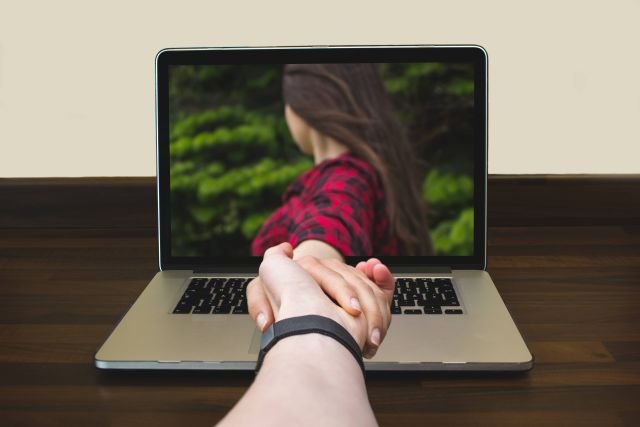 Long distance relationships_hand reaching through screen_AdobeStock_169228760 Compressed